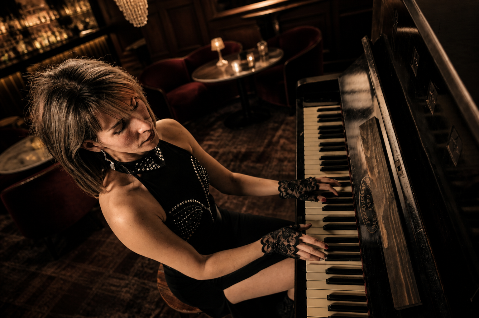 Lana Keys performing at a piano in a warm, candlelit lounge